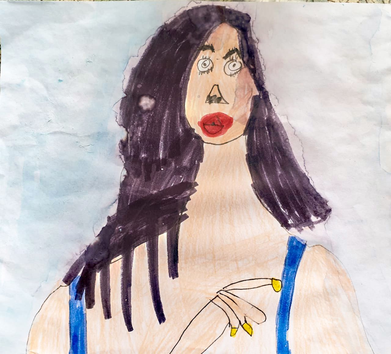 A child's mixed media drawing of a woman with black hair, red lips, and a blue shirt. Her right hand is in front of her chest with her index finger raised. The background is a faint blue watercolor.