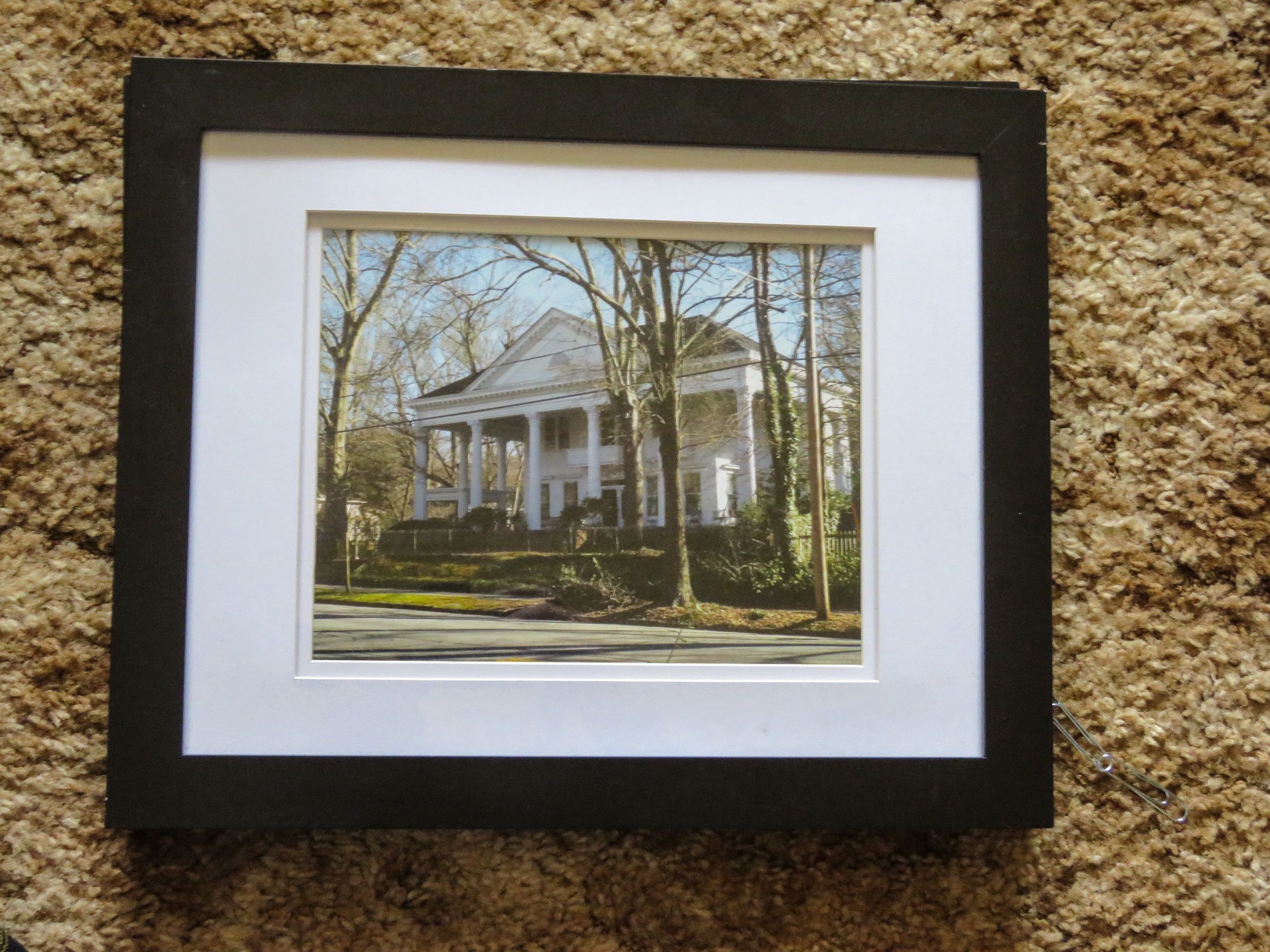 A framed photo of a white columned historic house